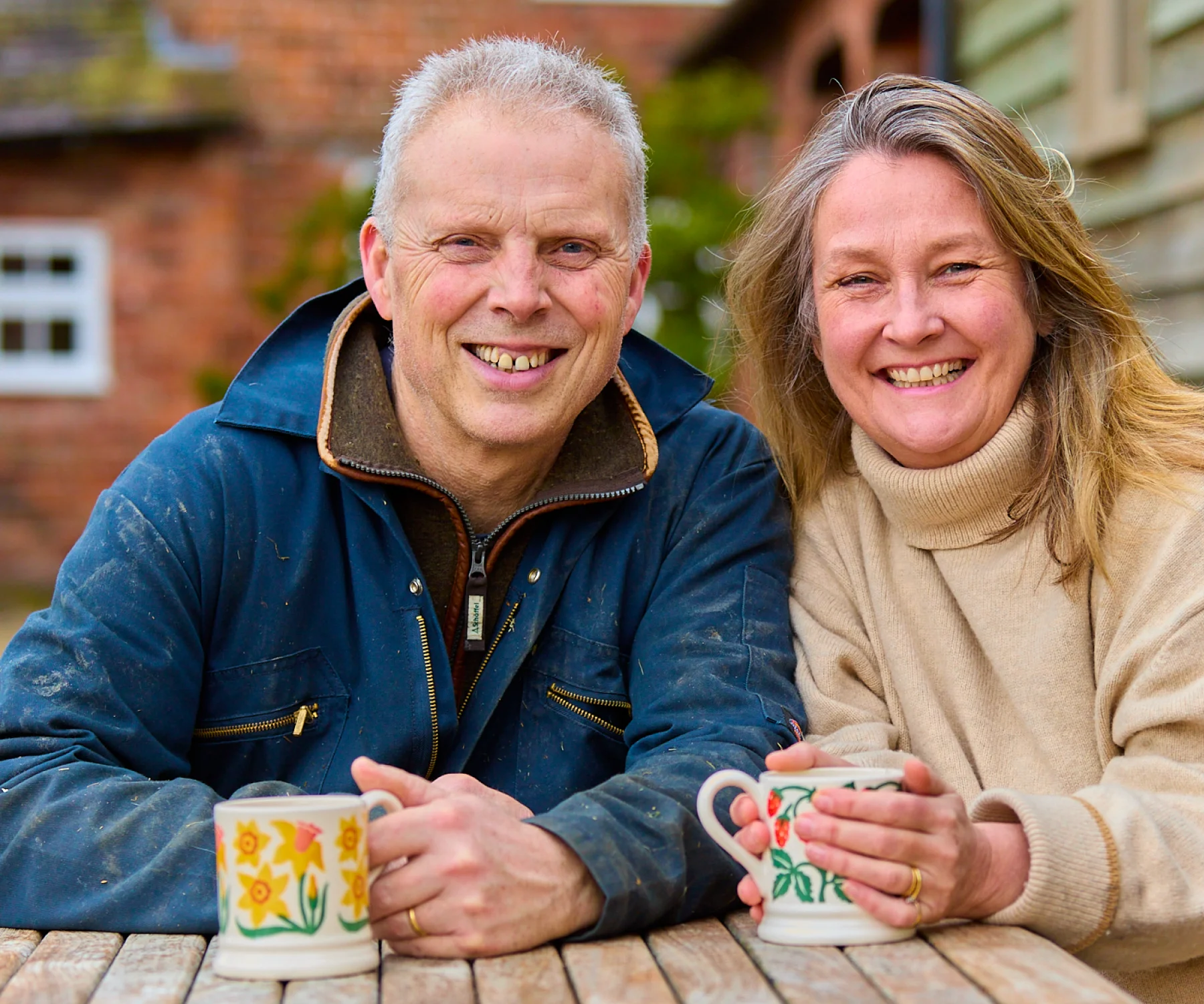 Marcus and Amy are your hosts when you stay at the luxury holiday cottages at Middle Farm, Shropshire. An image of them having a cup of tea in the farm's courtyard.